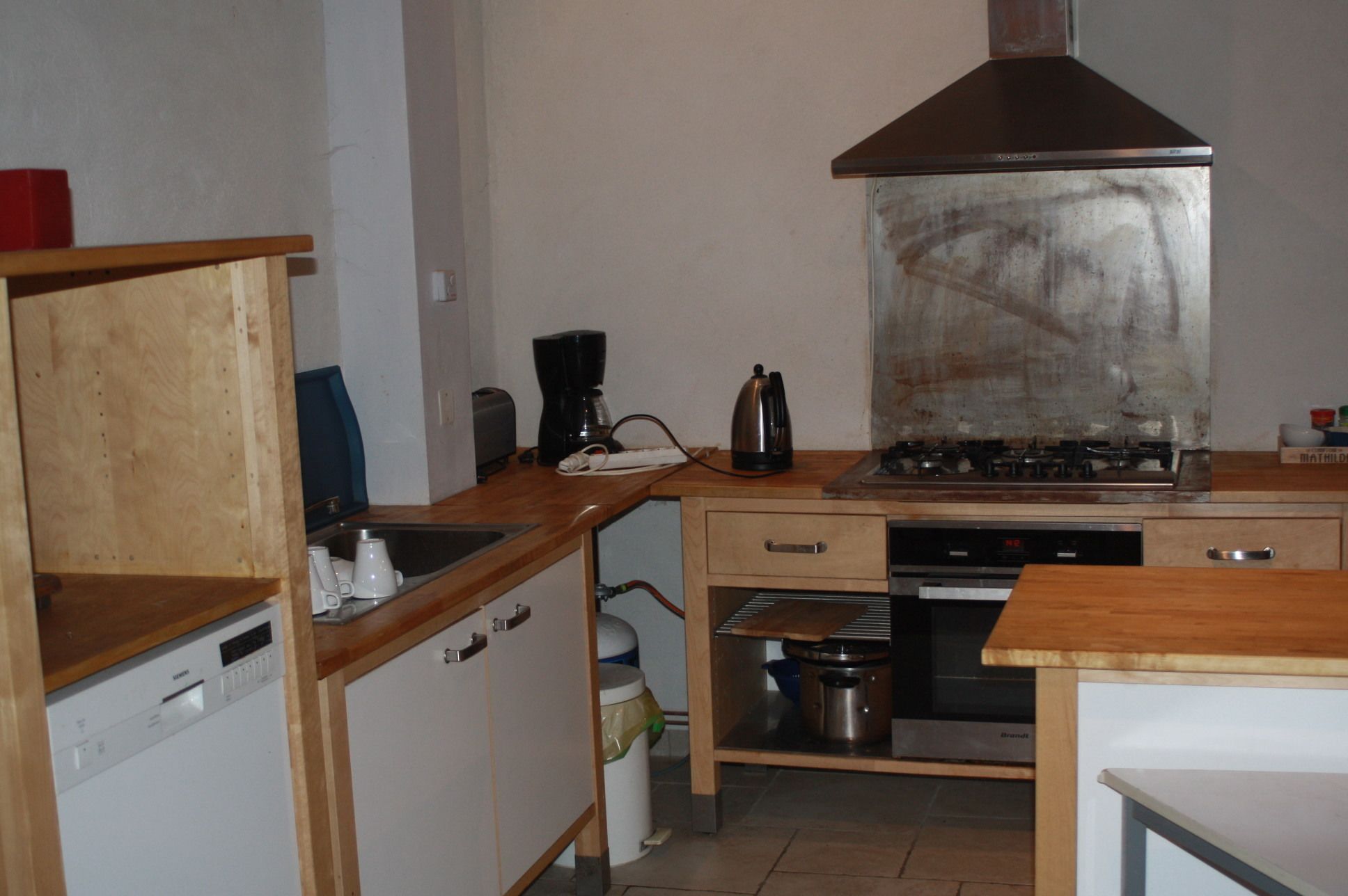 Une cuisine de taille réduite équipée d’une cuisinière, d’un évier et d’un lave-vaisselle.