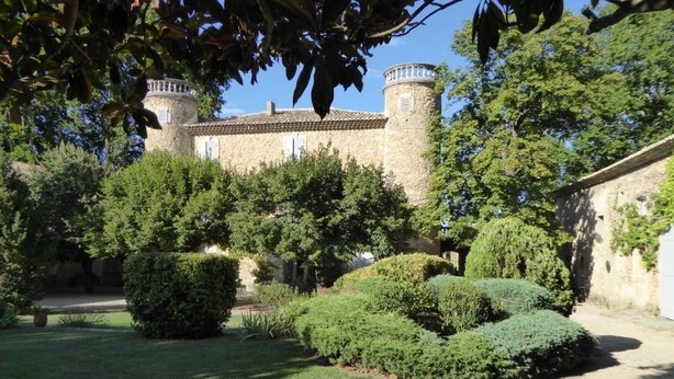 A courtyard with a stone building featuring a tower, surrounded by well-maintained hedges and trees. - Domaine de Lamartine chambres d'hotes (Pont-Saint-Esprit)
