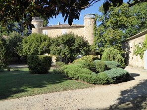 A courtyard with a stone building featuring a tower, surrounded by well-maintained hedges and trees. - Domaine de Lamartine chambres d'hotes (Pont-Saint-Esprit)