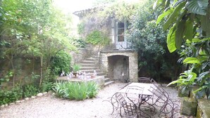 A rustic courtyard with a stone staircase leading to a wooden door, surrounded by lush greenery and a gravel path. - Domaine de Lamartine chambres d'hotes (Pont-Saint-Esprit)