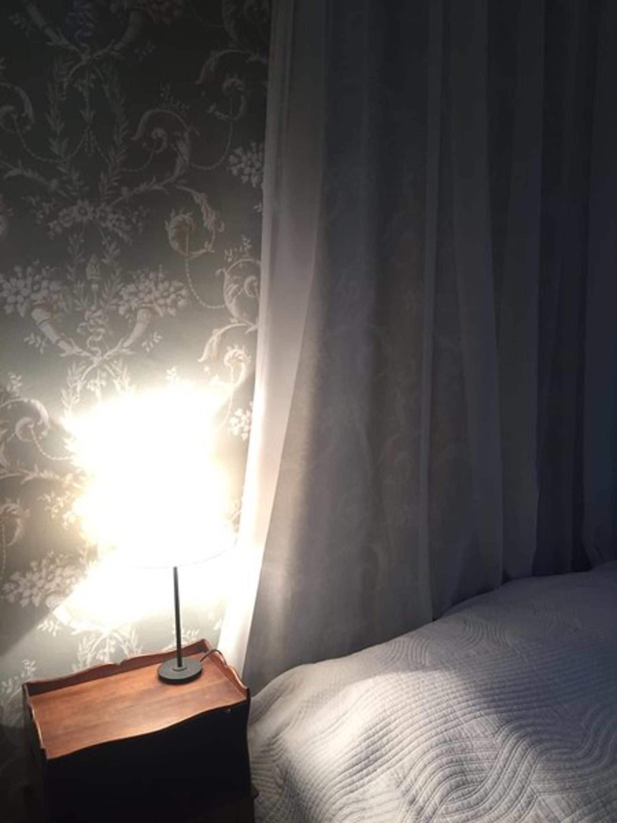 Une chambre à coucher avec un lit, une table de chevet et une lampe.