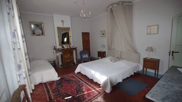 Ein Schlafzimmer mit Bett, Sessel, Schreibtisch, Spiegel und einer Kristallleuchtre.