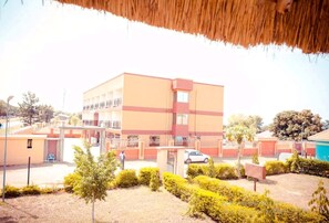 A multi-story building with a flat roof, surrounded by a well-maintained garden with trimmed bushes and a few trees. - Leosim Hotel (Pakwach)