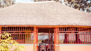 A thatched-roof structure with a covered seating area and a view of the surrounding landscape. - Leosim Hotel (Pakwach)