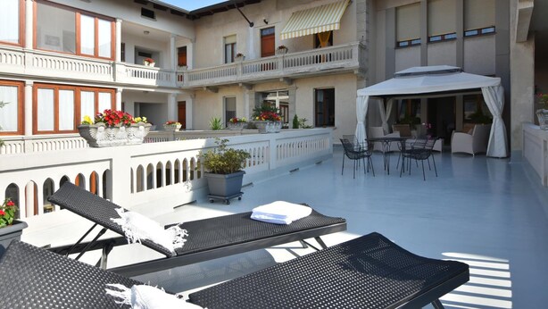 A spacious outdoor area with lounge chairs, a covered seating area, and potted plants. - Il Terrazzo B&B (Romagnano Sesia)