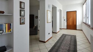 A hallway with a wooden door, framed pictures on the walls, and a patterned rug on the floor. - Il Terrazzo B&B (Romagnano Sesia)