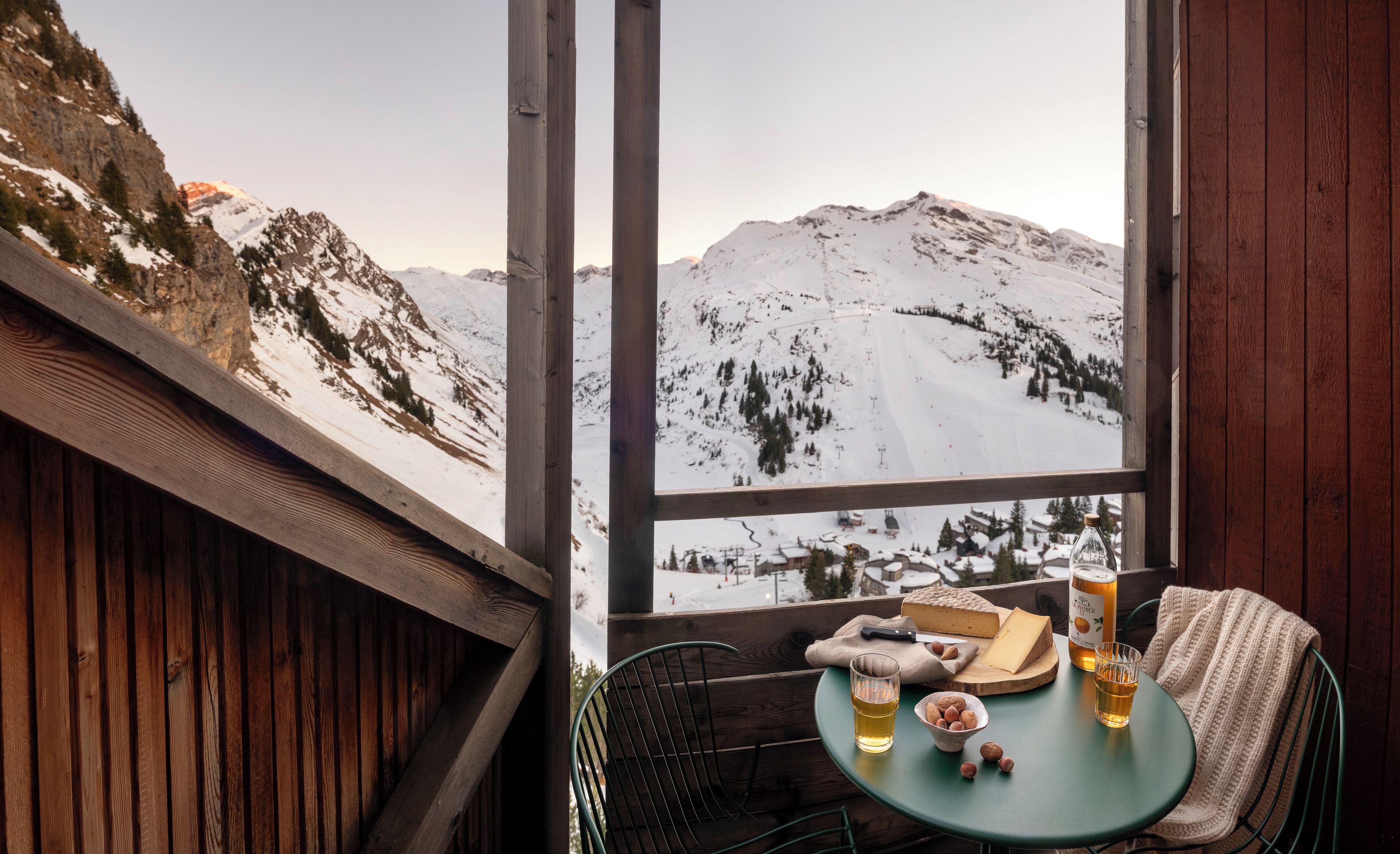Una terraza de madera con una mesa lista para una comida, con vista a una montaña nevada.