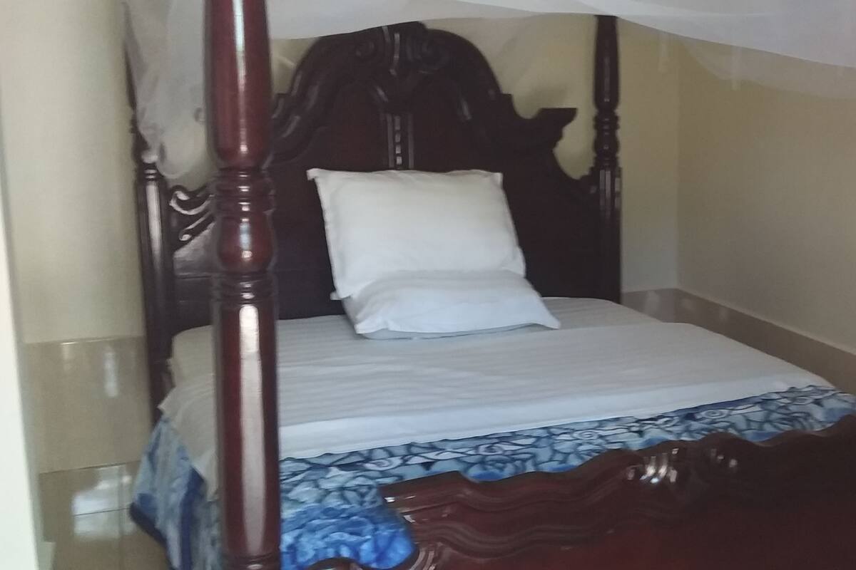 A four-poster bed with a white mattress and a blue patterned bedspread.