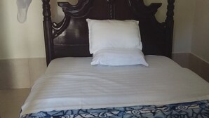 A neatly made bed with a white sheet and a patterned bedspread. - Mango Cottages & Recreation Center (Kakiri)