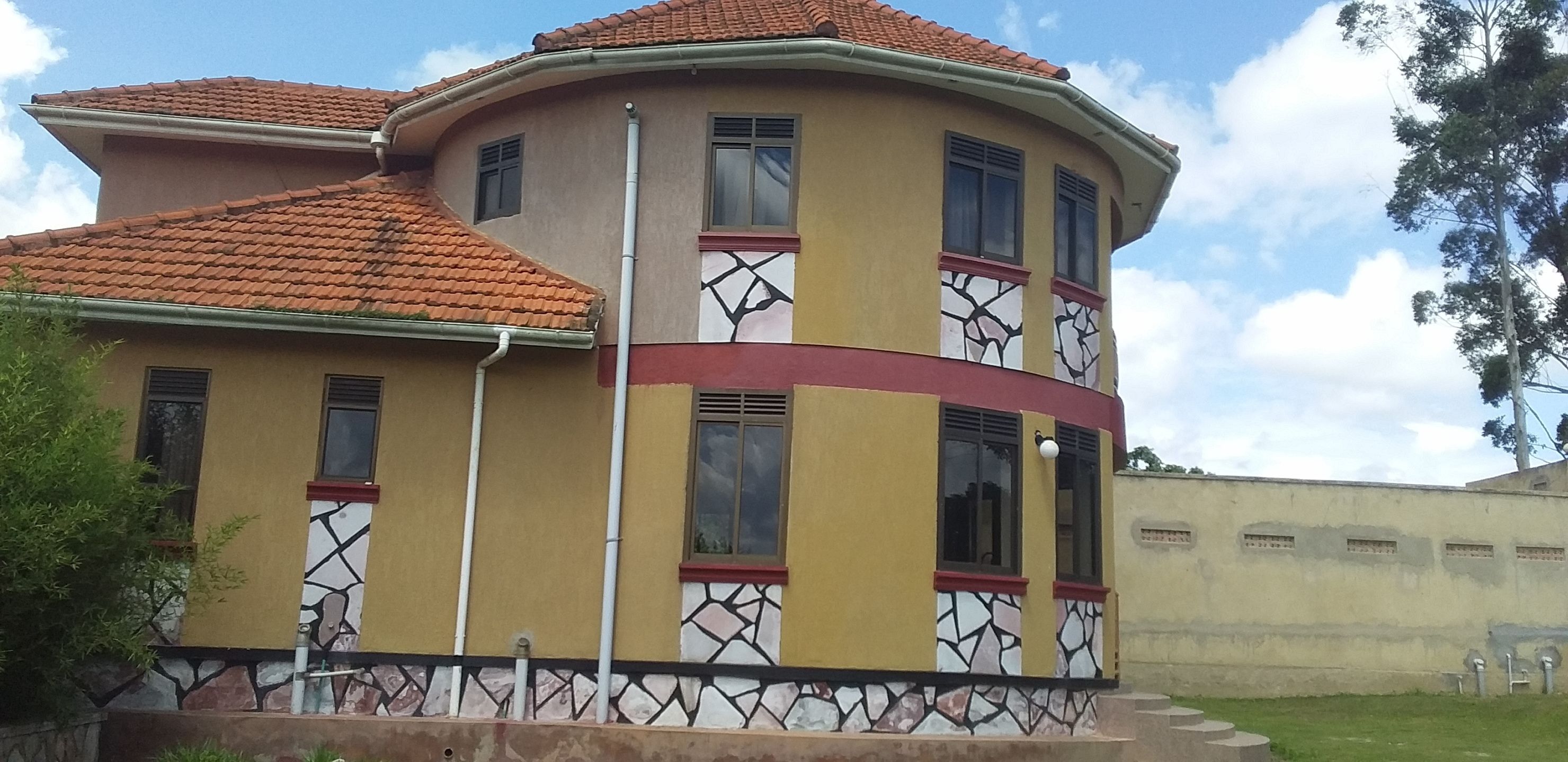 A two-story building with a curved roof, multiple windows, and a stone base.