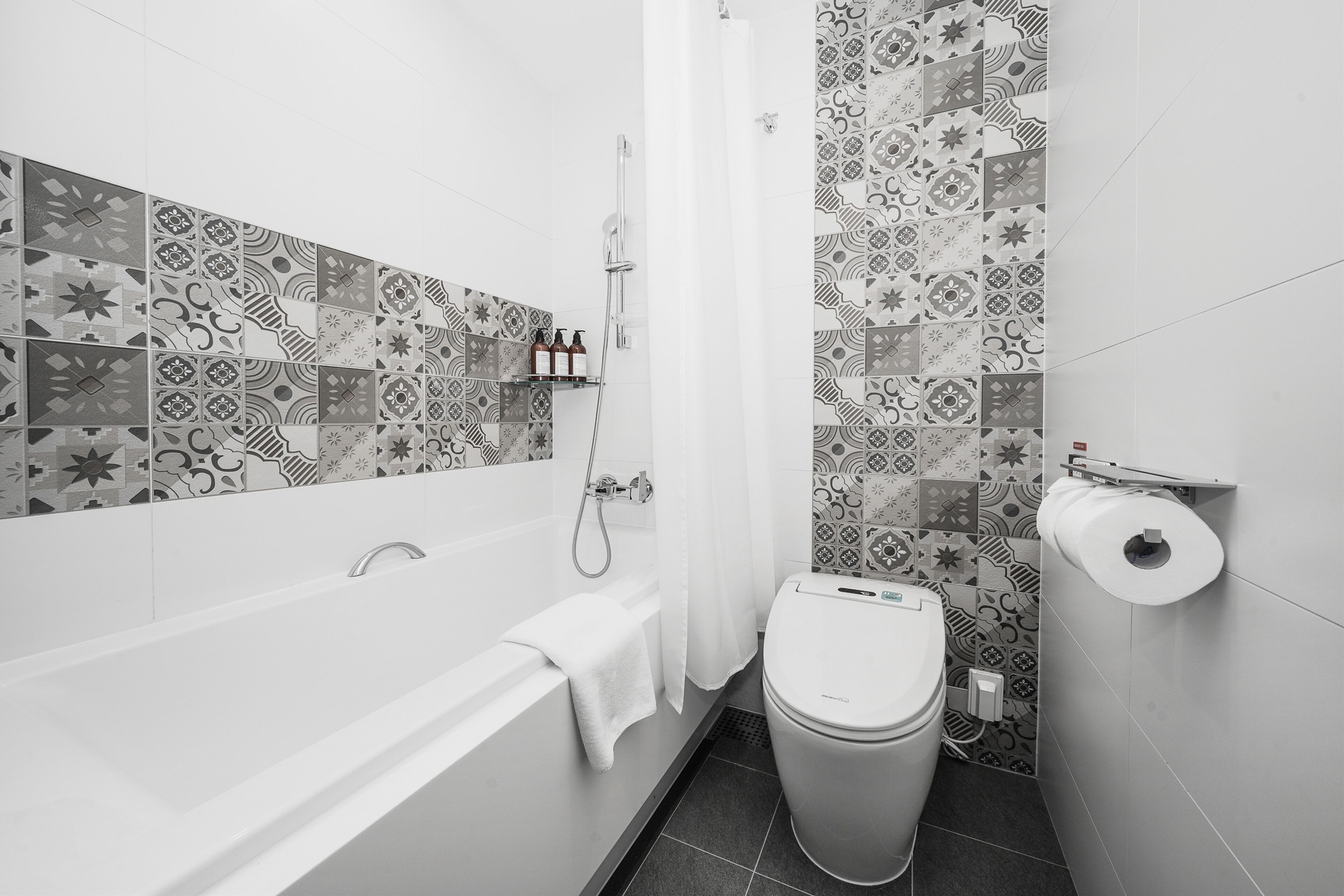 Een moderne badkamer met een badkuip, toilet en douche.