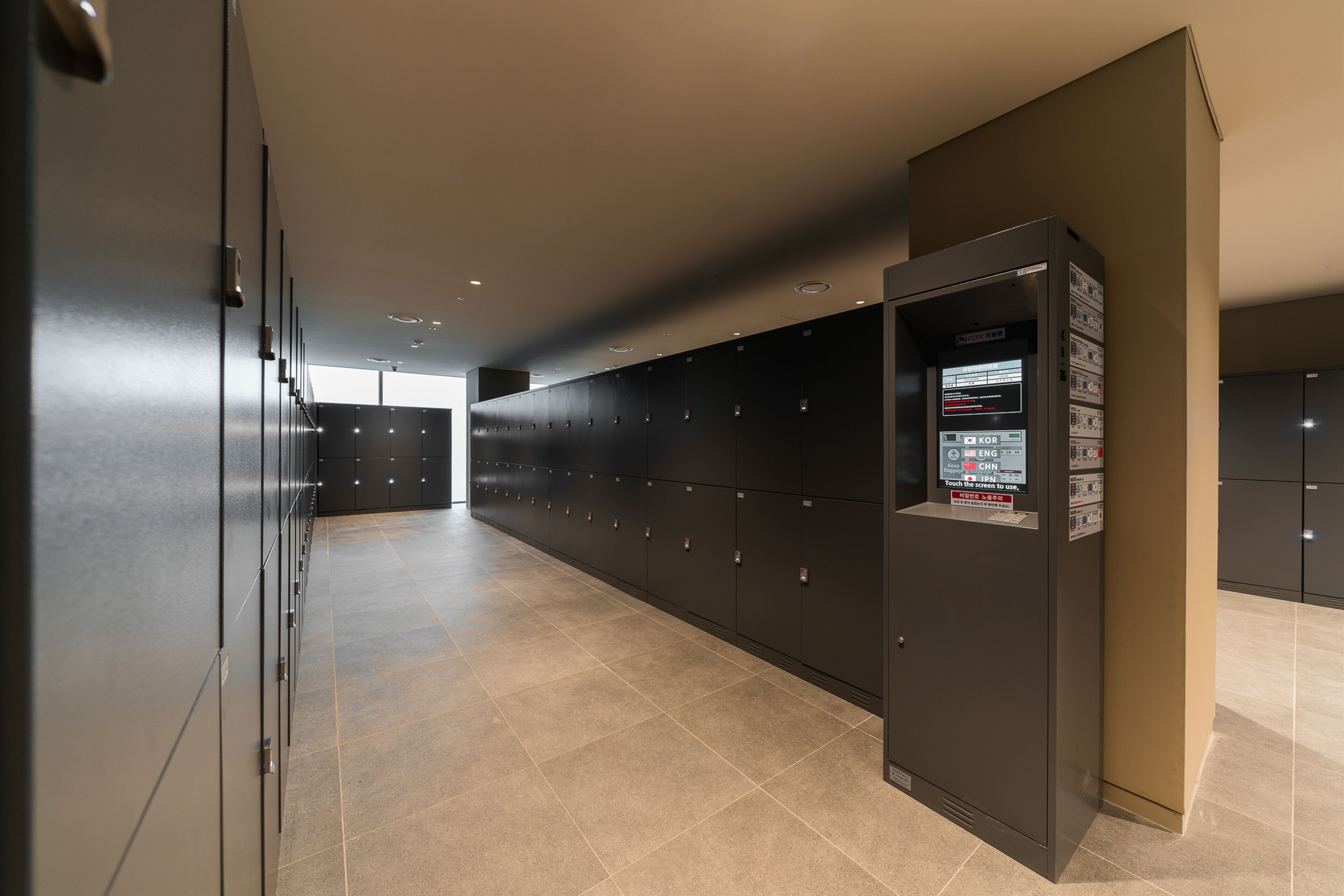 A modern hallway with lockers, a vending machine, and a door leading to another area.