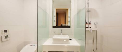 A modern bathroom with a glass-enclosed shower, a white sink, and a toilet.