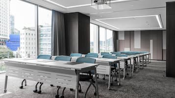 Un salón de conferencias con una larga mesa, sillas y un amplio ventanal con vista a la ciudad.