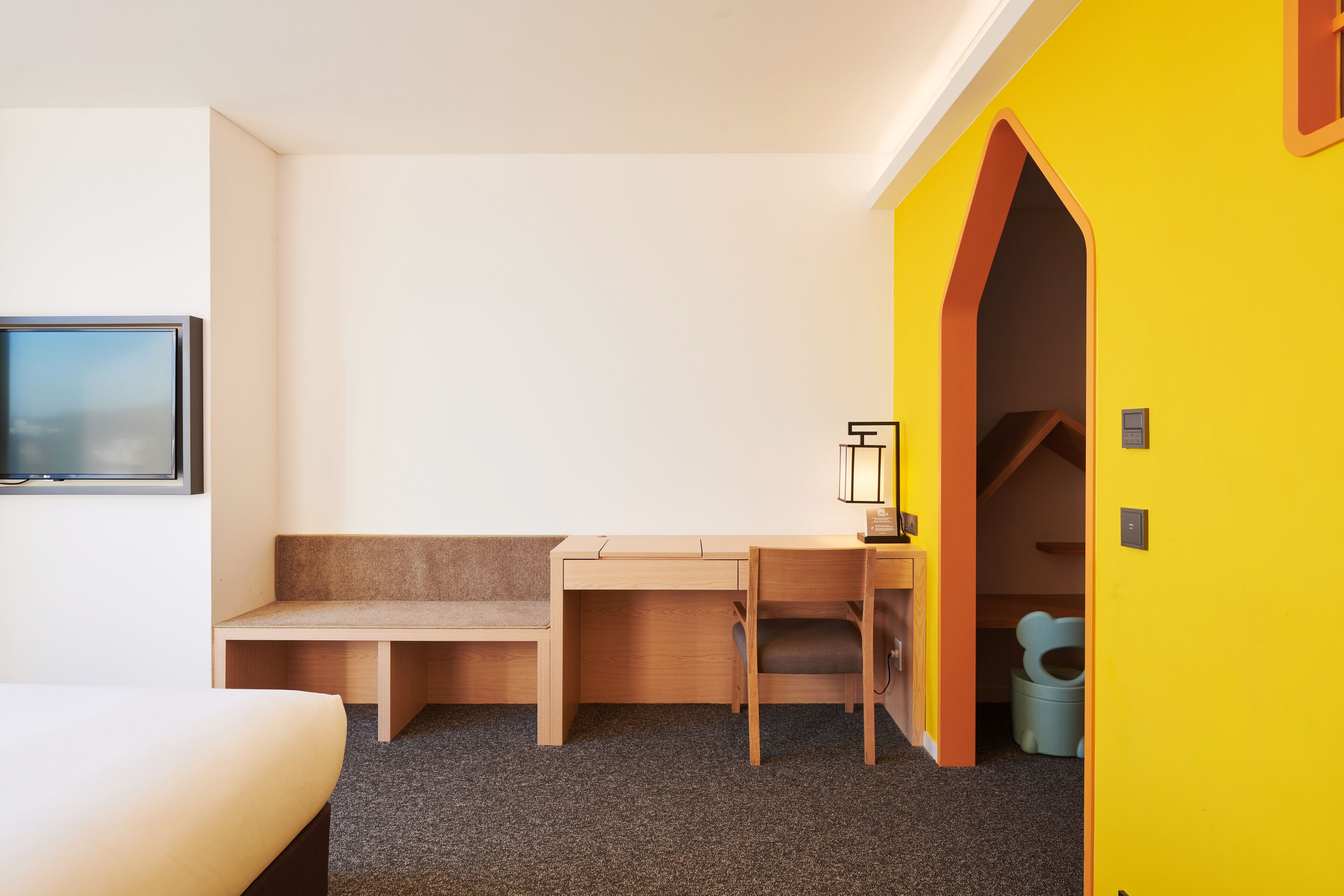 A hotel room with a bed, a desk, a chair, a small table, and a window.