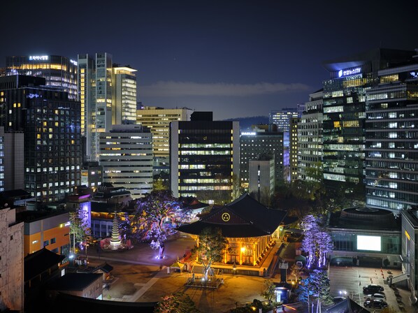 Un paisaje urbano nocturno con edificios modernos y un edificio tradicional con decoraciones iluminadas.