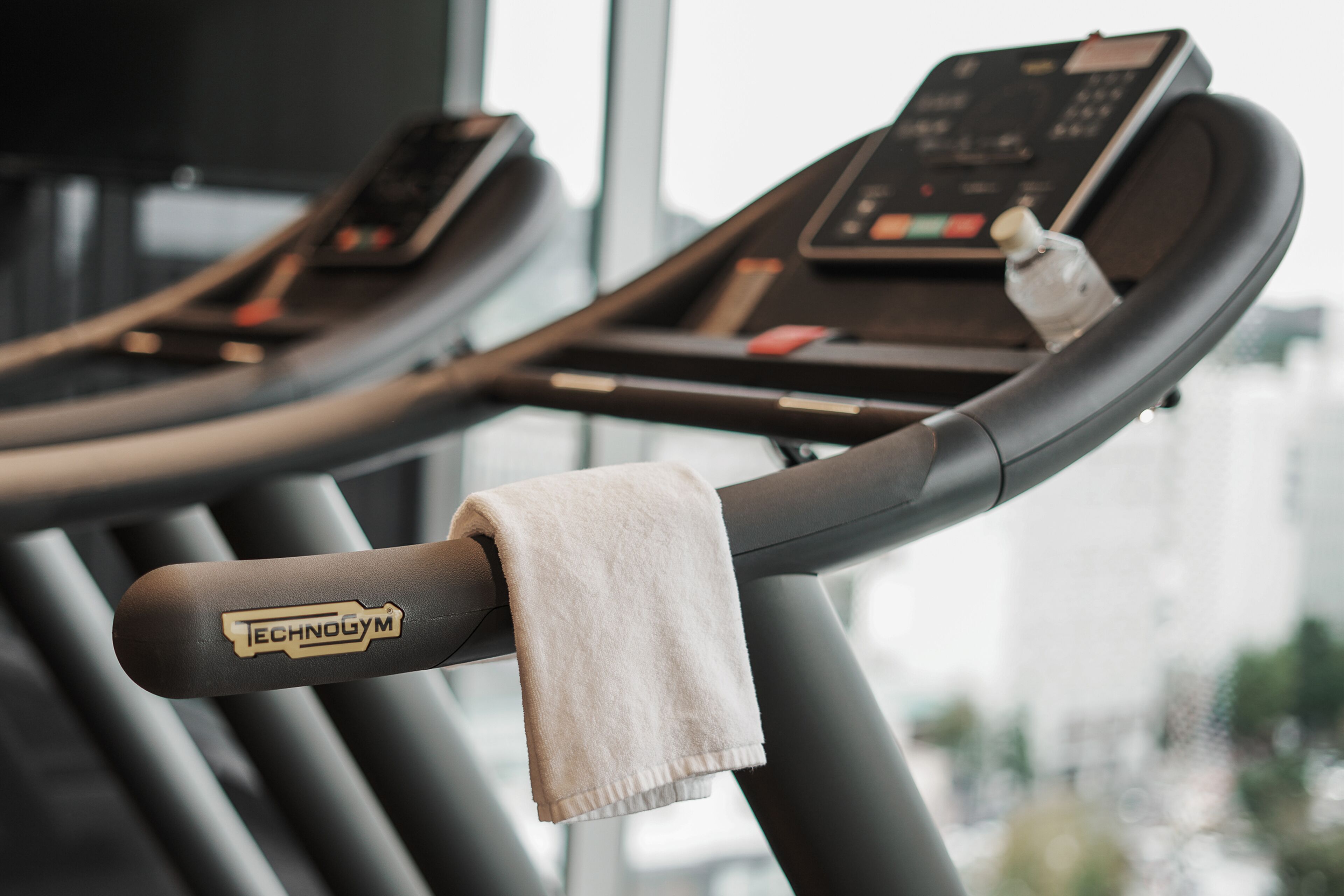 A treadmill with a towel draped over the handrail and a control panel.