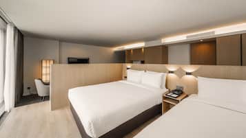 Una habitación de hotel moderna con dos camas, un escritorio y un televisor.