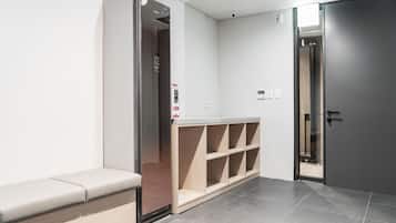 A modern elevator with a digital display, a bench, and a glass door.