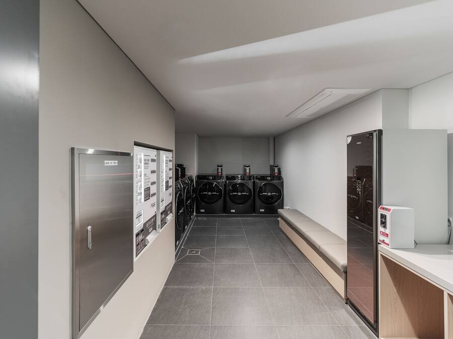 A laundry room with four washing machines and a refrigerator.