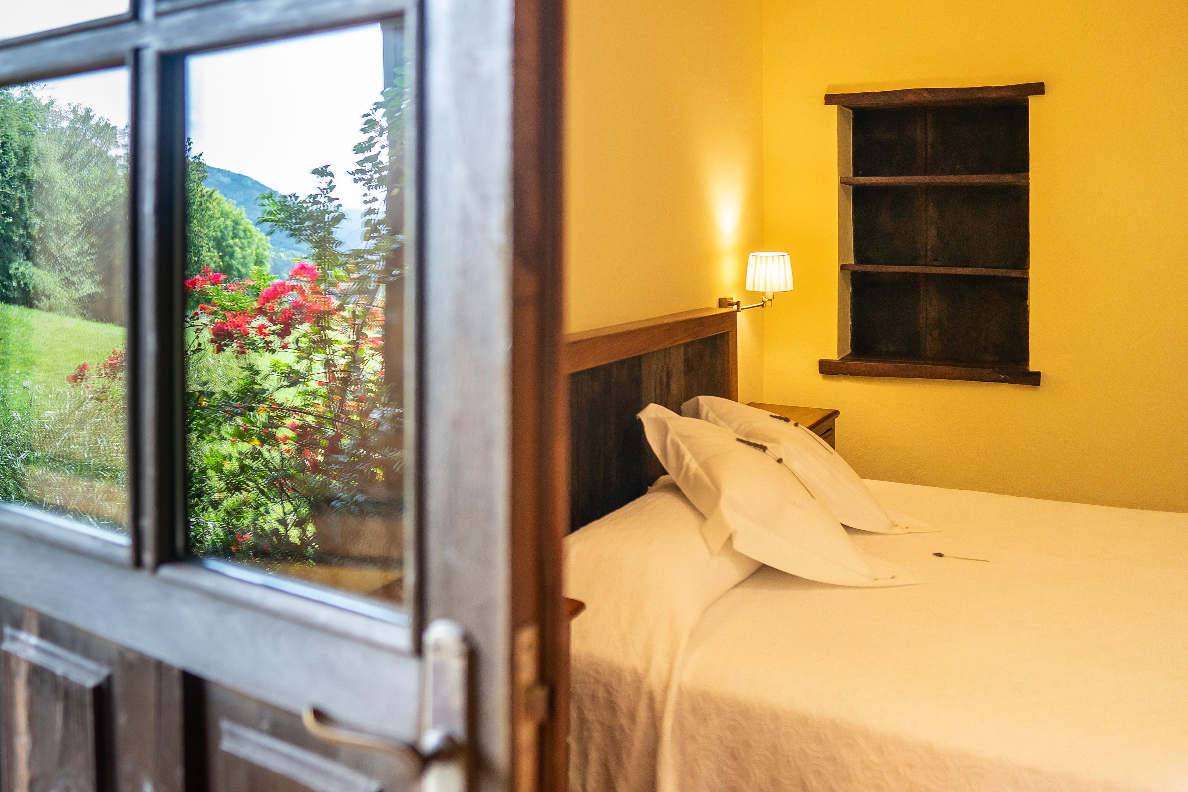 Una habitación con cama, ventana y estante de pared.