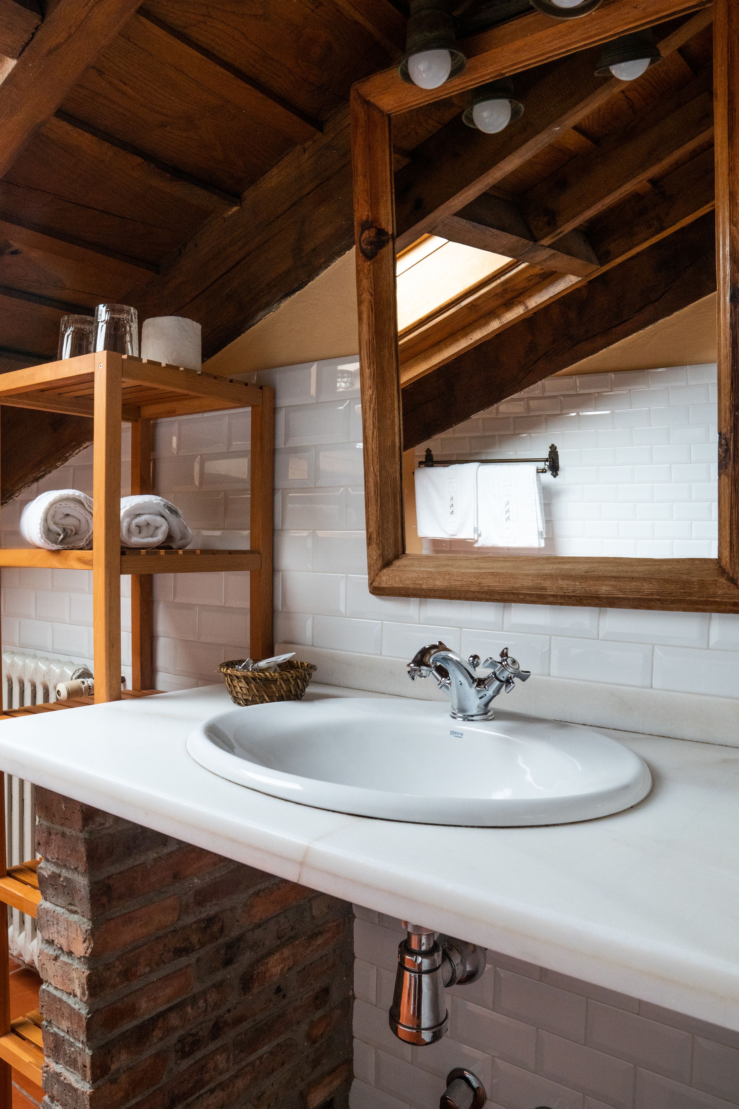 A bathroom with a white sink, wooden shelves, and a mirror.