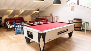 A cozy room with a pool table, leather sofas, and a billiards rack.