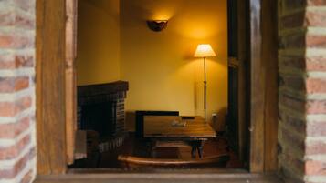 Una habitación acogedora con chimenea de ladrillo, una mesa de madera y una lámpara de pie.