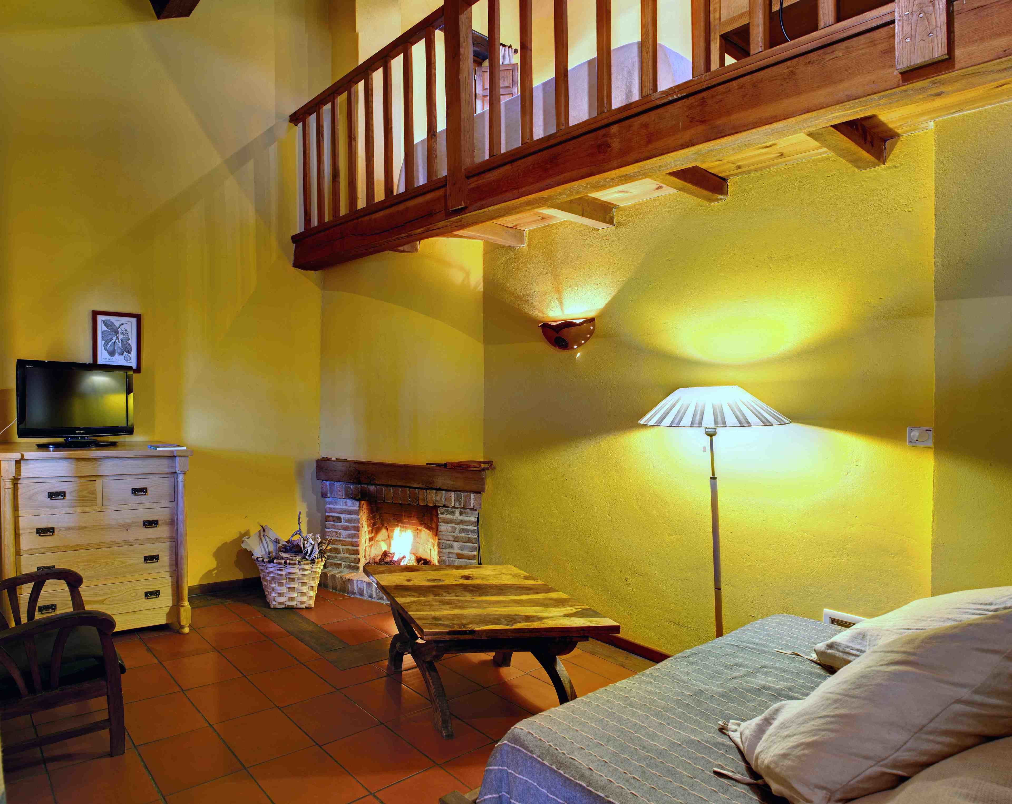 A cozy room with a fireplace, wooden furniture, and a television on a dresser.