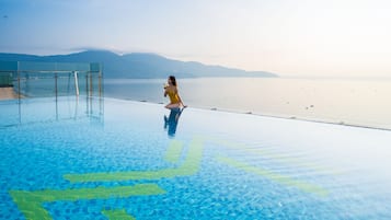 Una piscina al aire libre, sombrillas, sillones reclinables de piscina