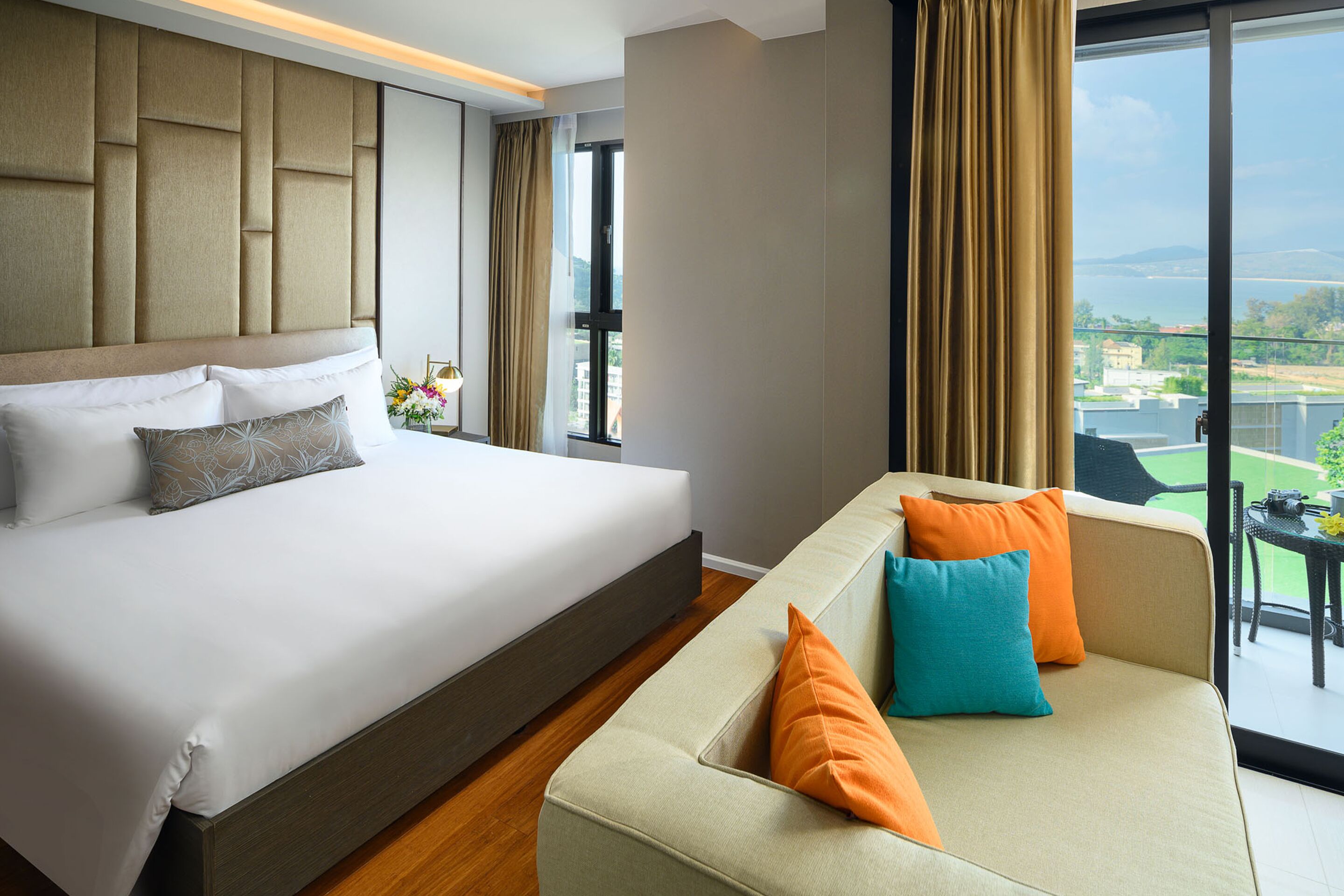 Ein Hotelzimmer mit einem großen Bett, einer Couch und Blick ins Freie.