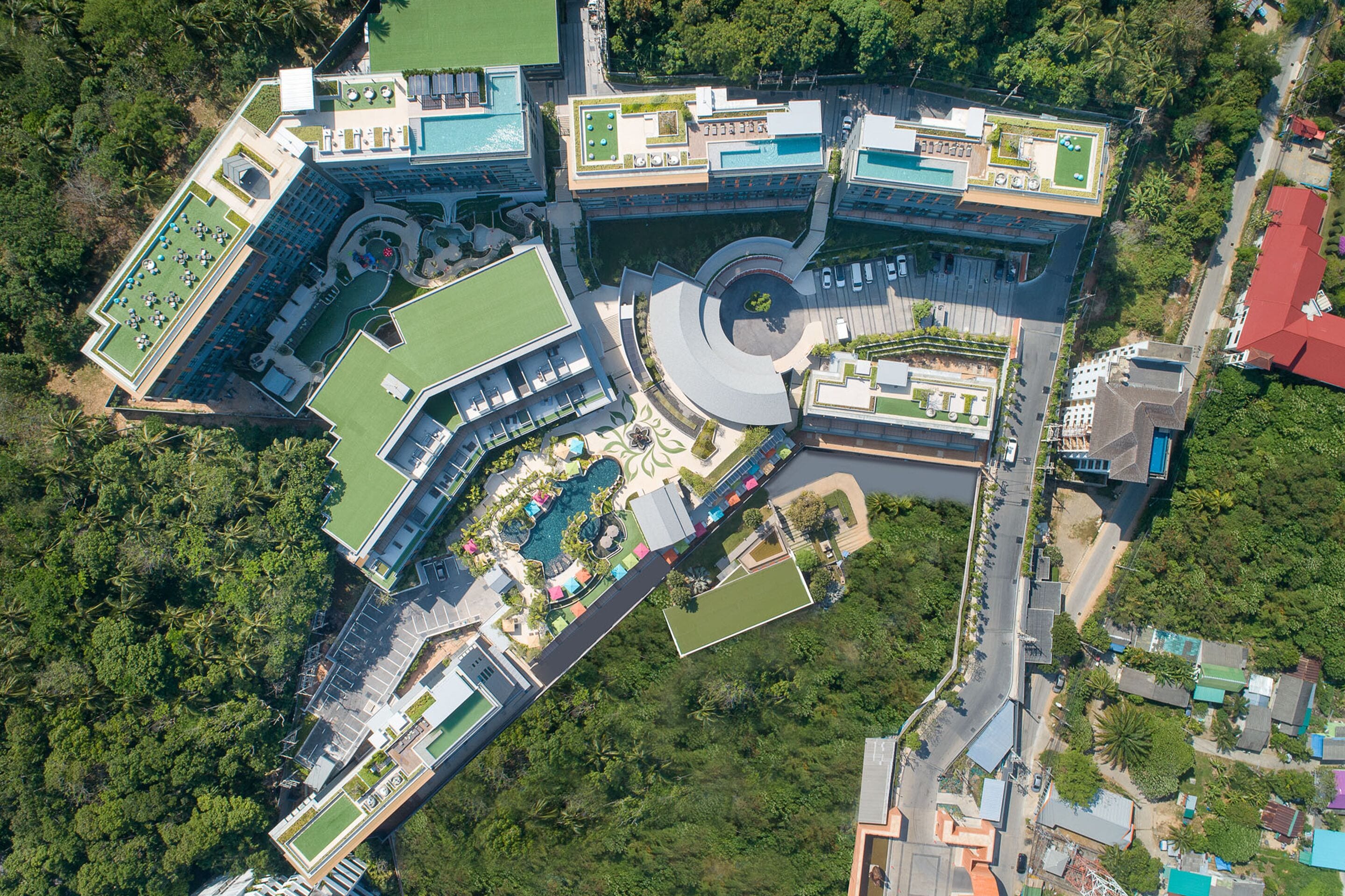Vista aérea de um hotel com vários edifícios, piscina e vegetação ao redor.