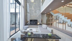 Una sala de estar moderna con un televisor grande, asientos cómodos y una escalera con escalones de madera.