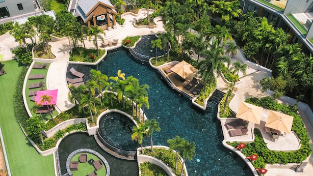Vista aérea de un resort con una piscina central, rodeado de palmeras y zonas de descanso.