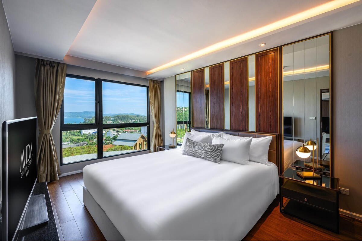 A modern hotel room with a large bed, a TV, and a view of the city.