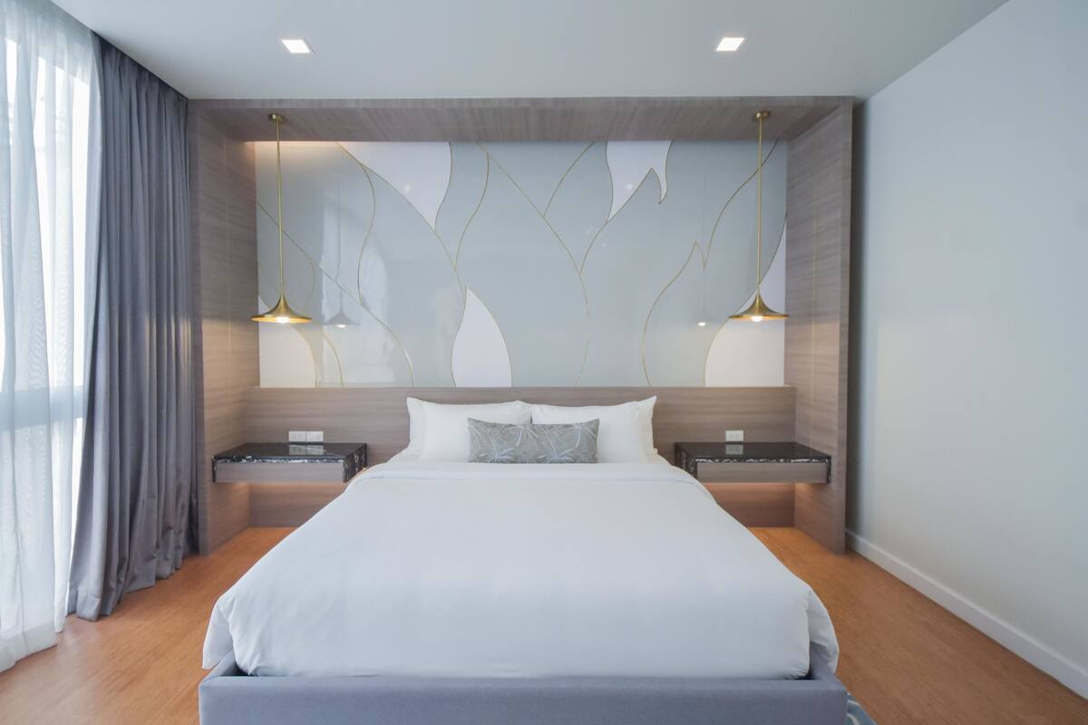 A modern bedroom with a large bed, two bedside tables, and a wall-mounted light fixture.