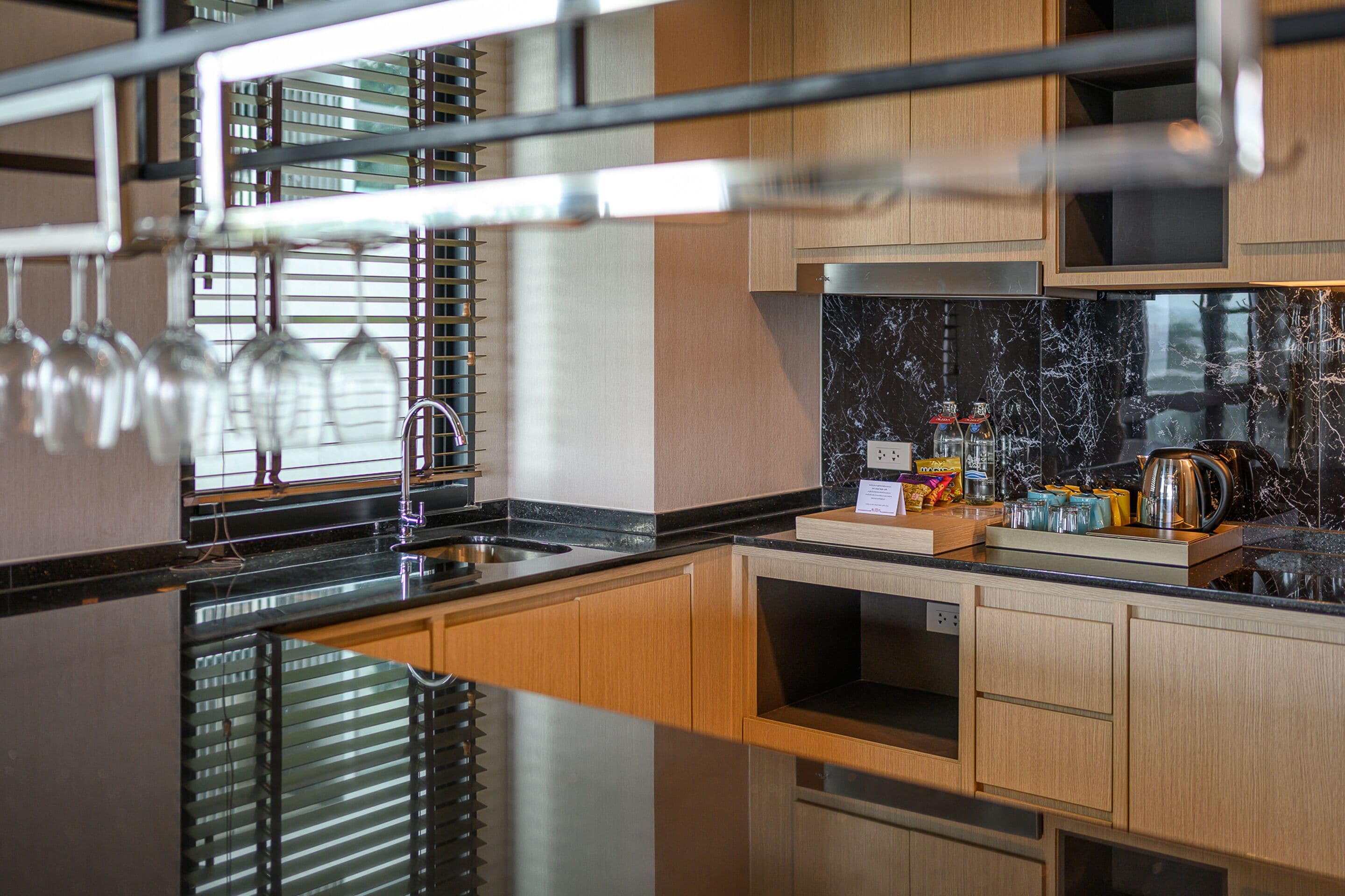 A modern kitchen with wooden cabinets, a black countertop, and a stainless steel sink.