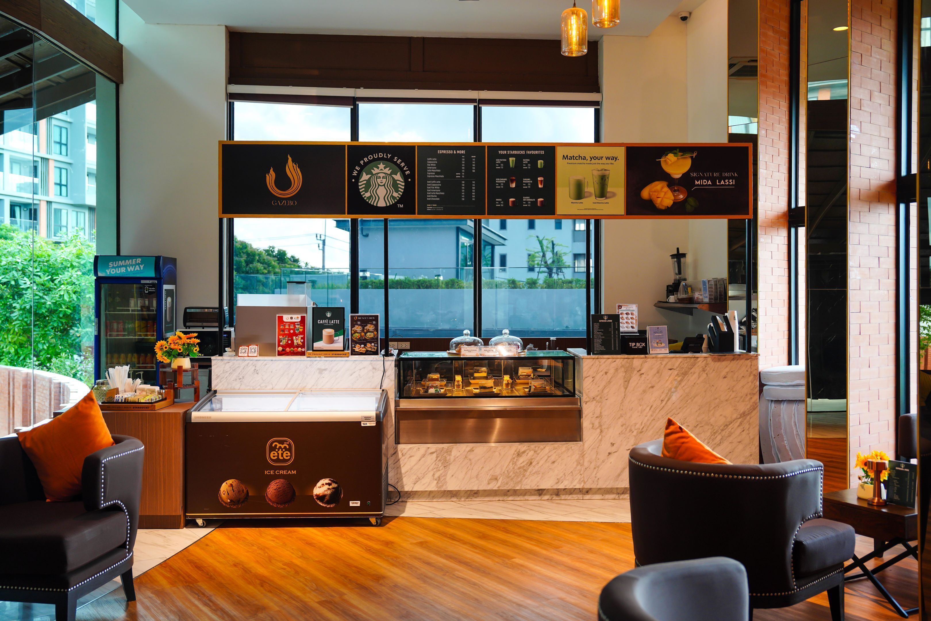 A modern cafe with a marble counter, a coffee machine, and a display of desserts.