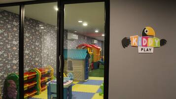 Uma área de recreação infantil com casinha, brinquedos e uma placa com a inscrição 'KIDDY PLAY'.
