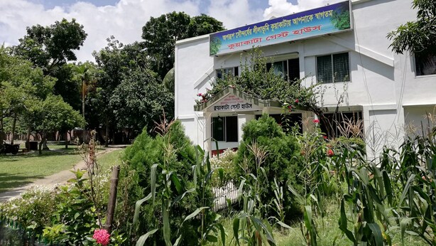 A building with a sign in a foreign language, surrounded by greenery and trees. - Kuakata Guest House (Kalapara)