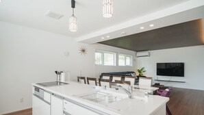 A modern kitchen with a large island, built-in appliances, and pendant lighting. - Lux Terrace Okinawa (Onna)