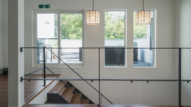 A staircase with a metal railing, a wooden floor, and a view of the outdoors through large windows. - Lux Terrace Okinawa (Onna)