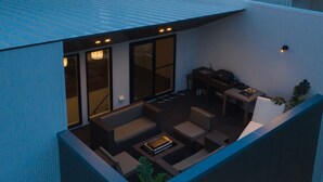 An outdoor patio with a sofa set, a table, and a grill area. - Lux Terrace Okinawa (Onna)