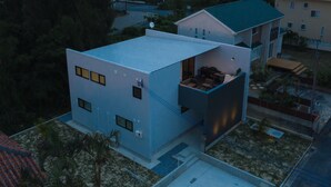 A modern two-story building with a flat roof, large windows, and a balcony. - Lux Terrace Okinawa (Onna)