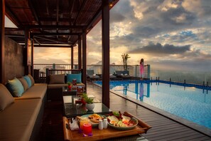 A poolside area with a dining table, lounge chairs, and a view of the pool. - Cozy Savvy Boutique Hotel Hoi An (Da Nang)