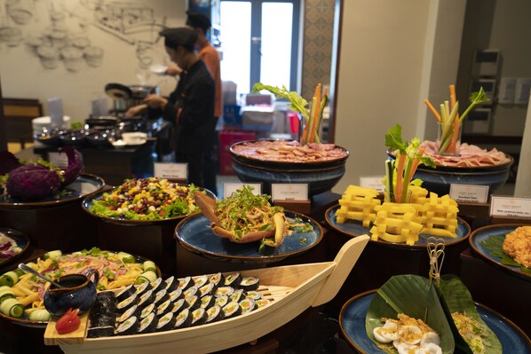 Un buffet proposant une variété de plats, notamment des sushis, des salades et d’autres amuse-gueules.