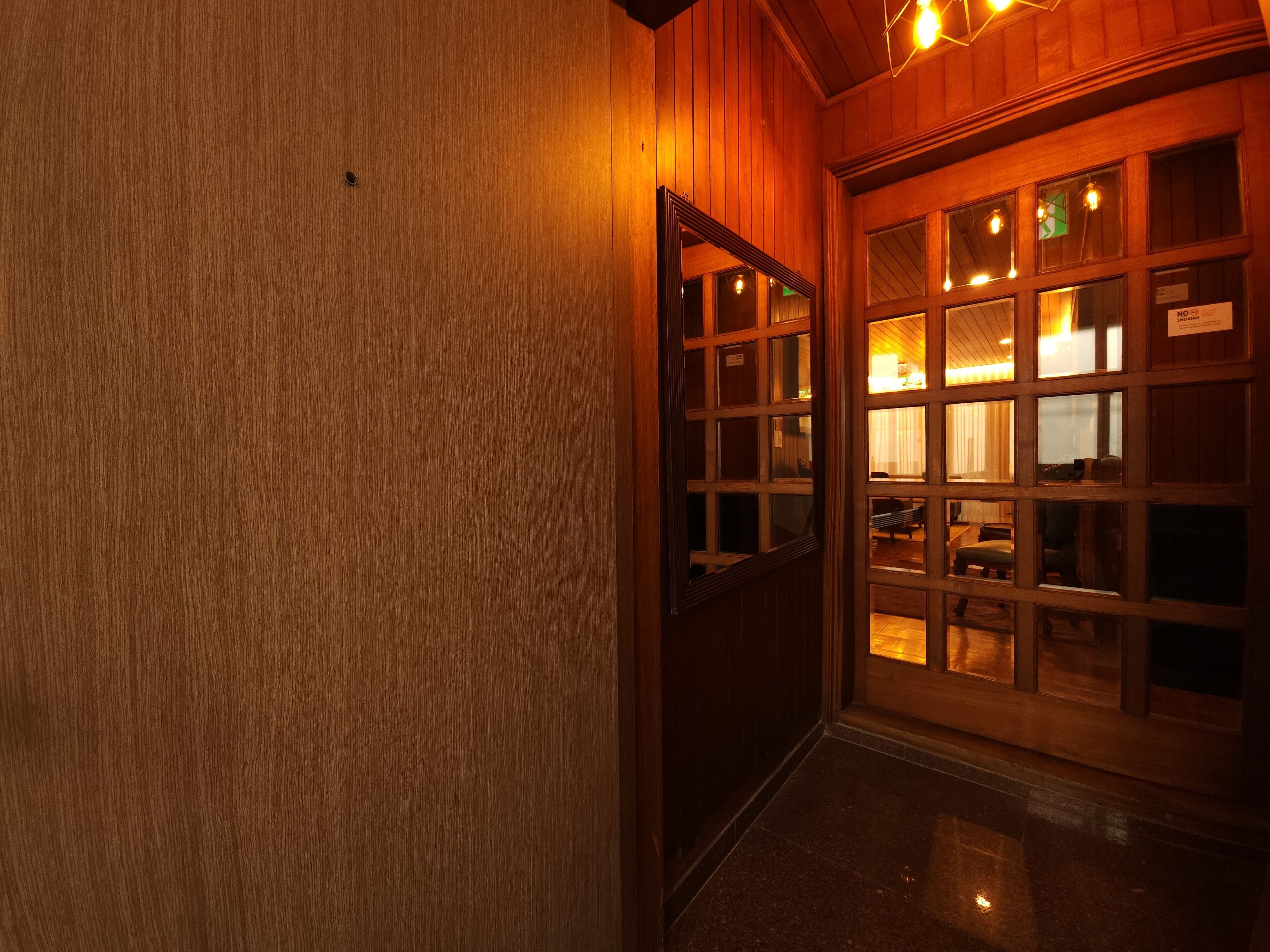 A wooden interior hallway with a door leading to a room with multiple windows and a sign that reads "NO SMOKING".