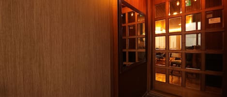 A wooden interior hallway with a door leading to a room with multiple windows and a sign that reads "NO SMOKING".