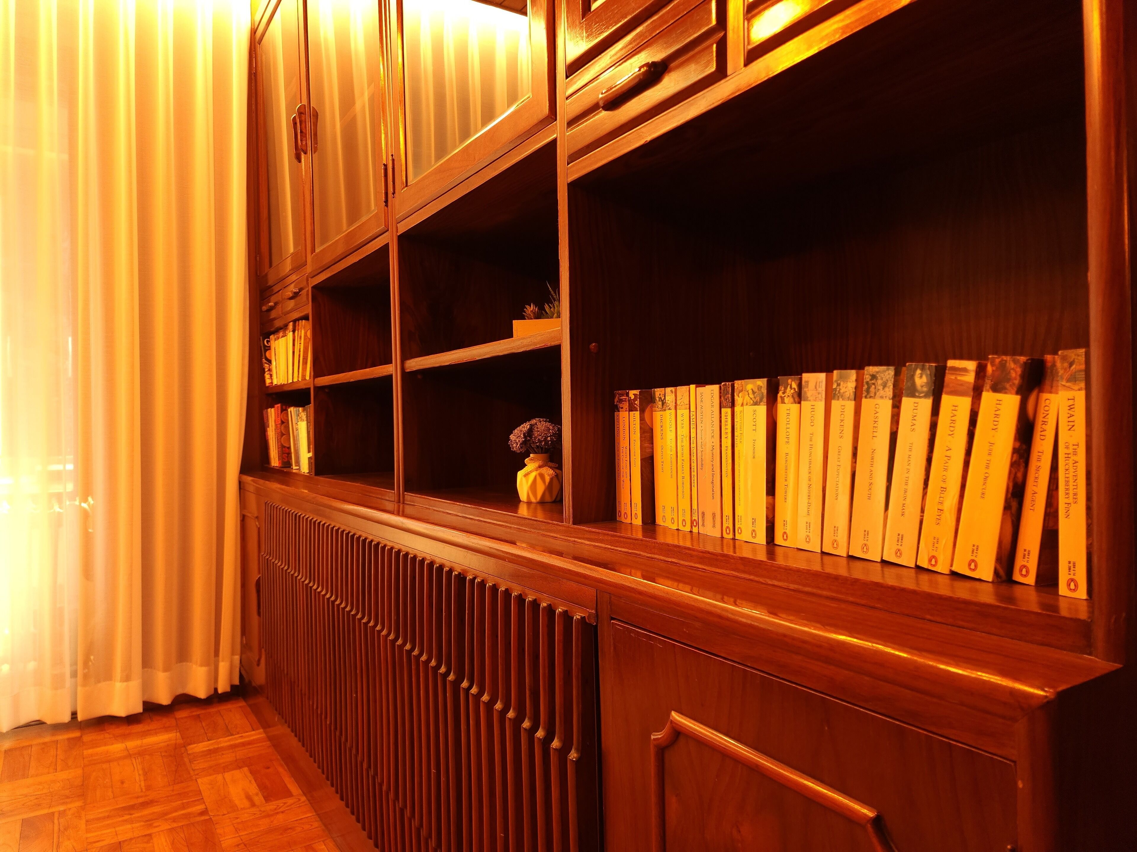 A wooden bookshelf with books and a vase.