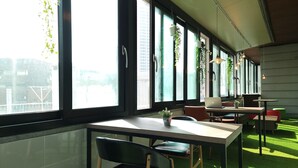 A modern office space with large windows, green artificial grass, and multiple seating areas. - OYO Hostel Myeongdong 5 (Seoul)
